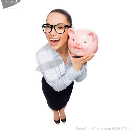 Image of happy businesswoman in eyeglasses with piggy bank