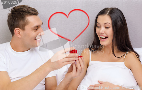 Image of man giving woman little red box and ring in it