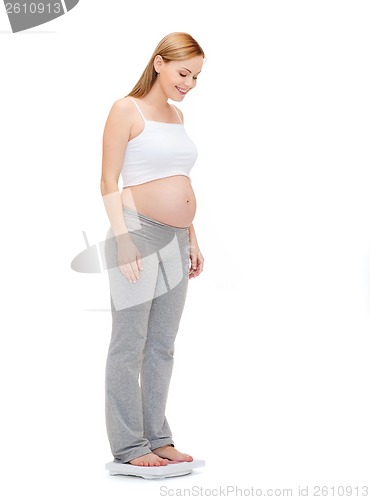 Image of happy pregnant woman weighting herself