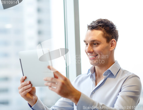 Image of smiling businessman with tablet pc in office