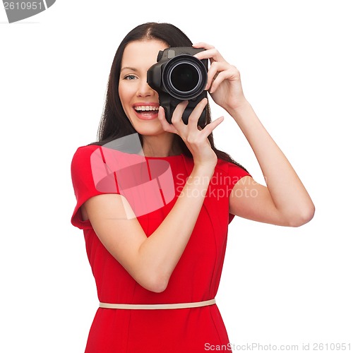 Image of smiling woman taking picture with digital camera