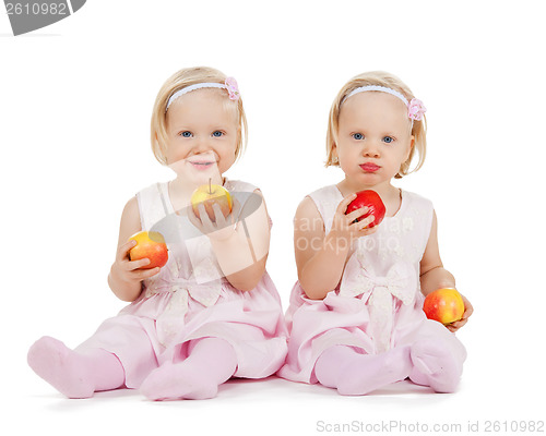 Image of two identical twin girls playing with apples