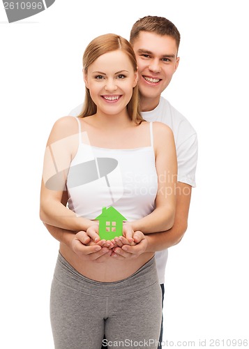 Image of happy young family expecting child with house