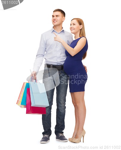 Image of happy young family expecting child pointing finger