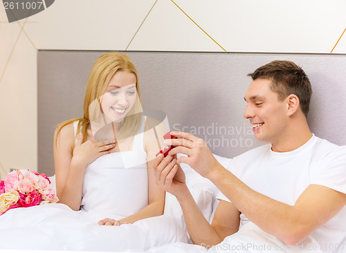 Image of man giving woman little red box and ring in it