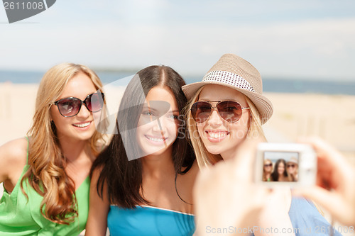 Image of girls taking photo with digital camera in cafe