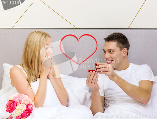 Image of man giving woman little red box and ring in it