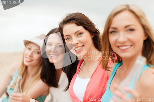 Image of smiling girls with drinks on the beach