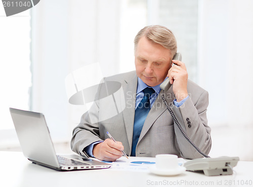 Image of busy older businessman with laptop and telephone