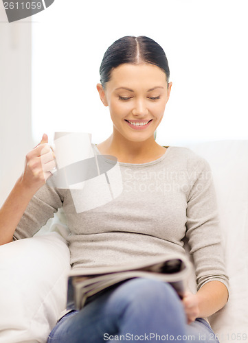 Image of woman with cup of coffee reading magazine at home