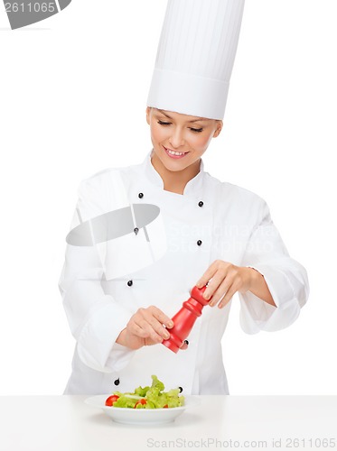Image of smiling female chef with preparing salad