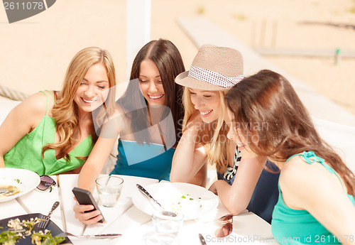 Image of girls looking at smartphone in cafe on the beach