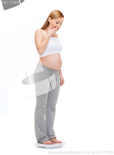 Image of amazed pregnant woman weighting herself