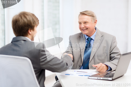 Image of older man and young man shaking hands in office