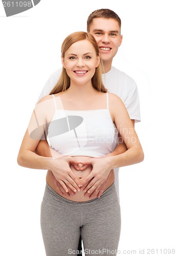 Image of happy young family expecting child with heart