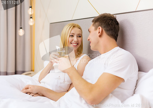 Image of smiling couple with champagne glasses in bed