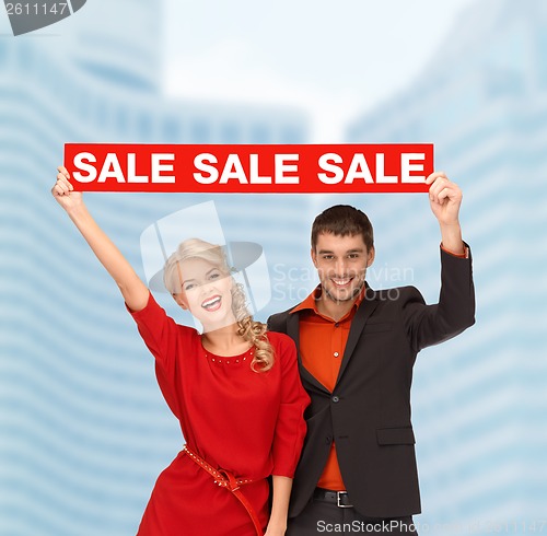 Image of smiling woman and man with red sale sign