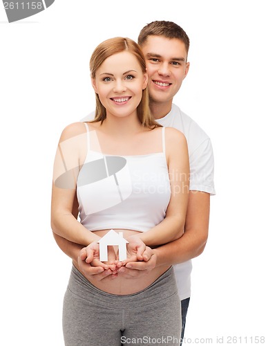 Image of happy young family expecting child with house