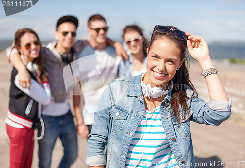 Image of teenage girl with headphones and friends outside