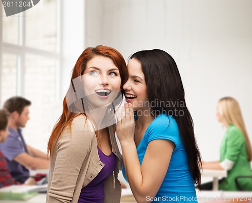 Image of two smiling girls whispering gossip