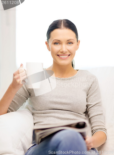 Image of woman with cup of coffee reading magazine at home