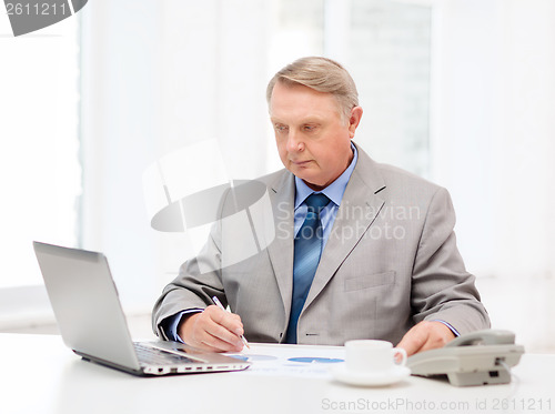 Image of busy older businessman with laptop and telephone