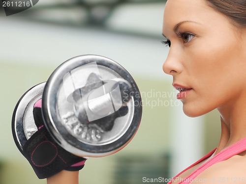 Image of concentrated woman with dumbbells in gym