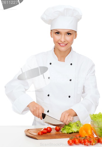 Image of smiling female chef chopping vagetables