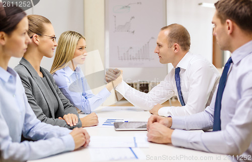 Image of businesswoman and businessman arm wrestling