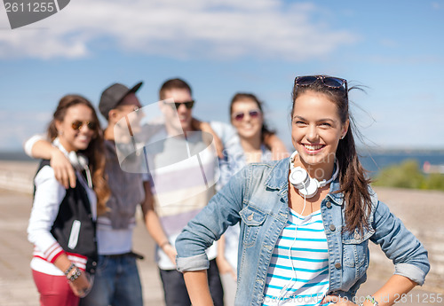 Image of teenage girl with headphones and friends outside