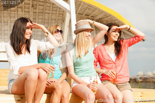 Image of smiling girls with drinks on the beach