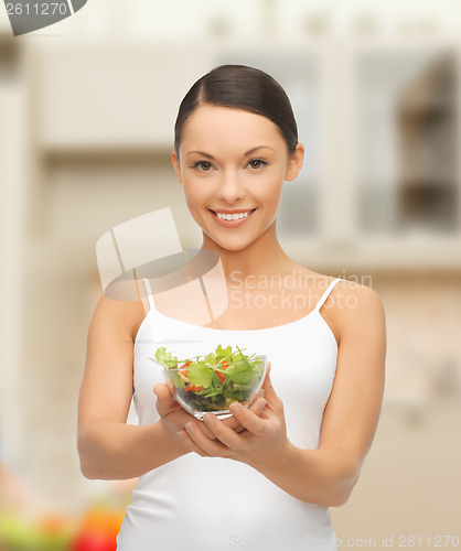 Image of healthy woman holding bowl with salad in kitchen