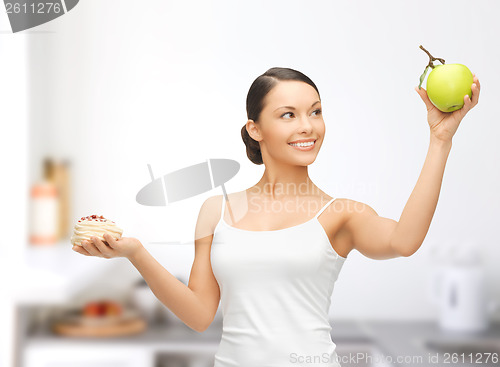 Image of sporty woman with apple and cake in kitchen