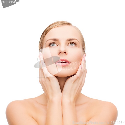 Image of beautiful woman touching her face and looking up