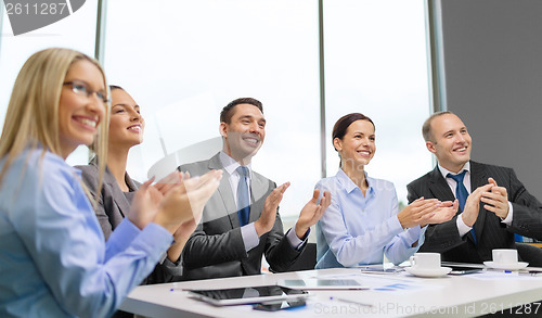 Image of business team with laptop clapping hands