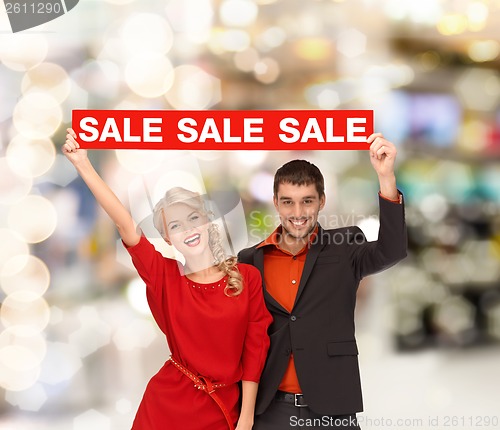 Image of smiling woman and man with red sale sign