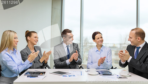 Image of business team with laptop clapping hands