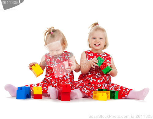 Image of two twin girls in red dresses playing with blocks