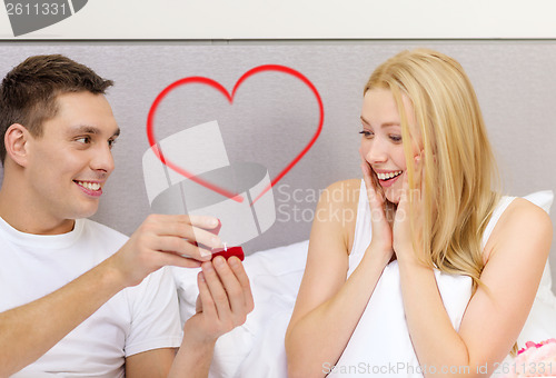 Image of man giving woman little red box and ring in it