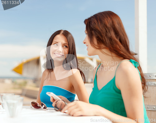 Image of girls looking at smartphone in cafe on the beach