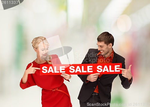 Image of woman and man pointing finger to red sale sign