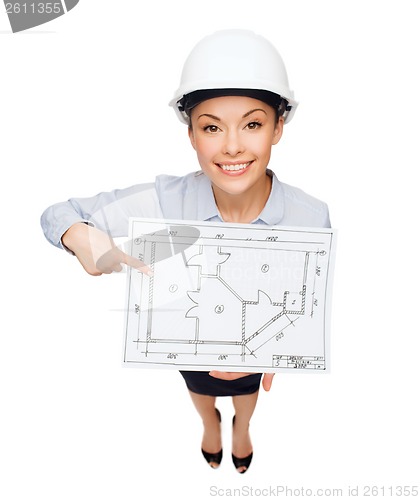 Image of businesswoman in helmet showing with blueprint