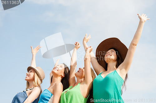 Image of smiling girls with hands up on the beach