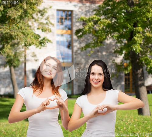 Image of two smiling girls showing heart with hands