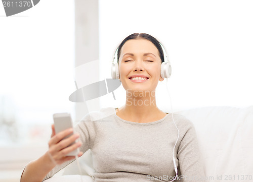 Image of woman with smartphone and headphones at home