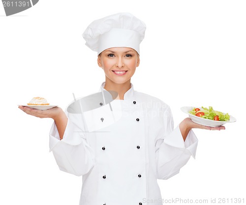 Image of smiling female chef with salad and cake on plates