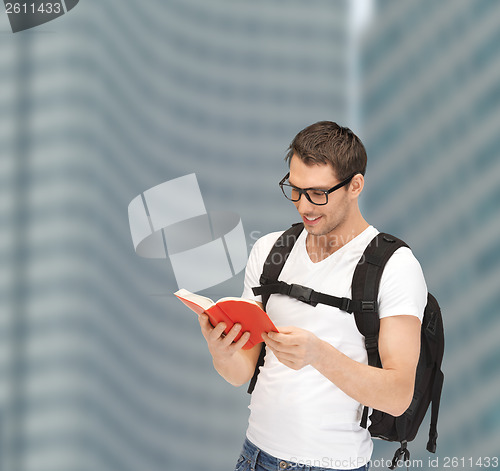 Image of student in eyeglasses with backpack and book