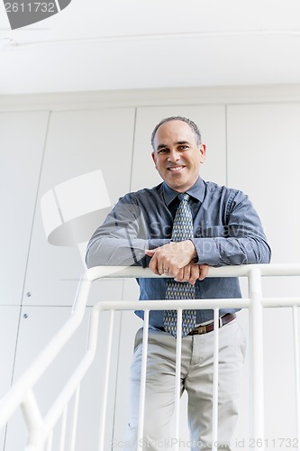 Image of Businessman standing in office hallway smiling