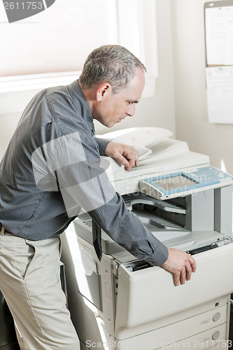 Image of Man opening photocopier in office