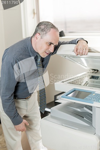 Image of Man having problem with photocopier in office